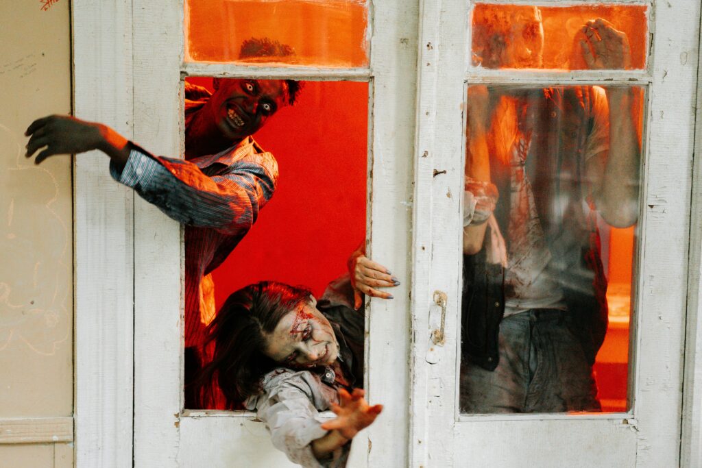 Zombies breaking through a door in a vivid horror scene with intense red lighting.